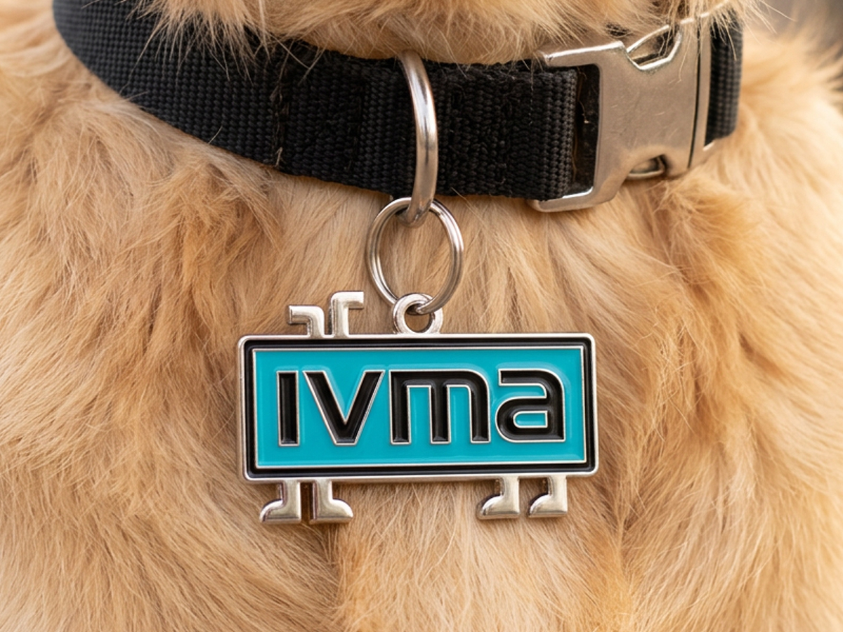 An IVMA enamel pet tag in teal and black hanging from a dog's collar